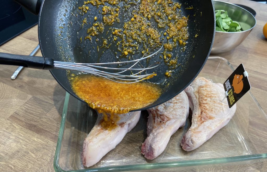 On verse le mélange d'orange, d'huile, de miel et de piment d'espelette sur les côtes de porc.
