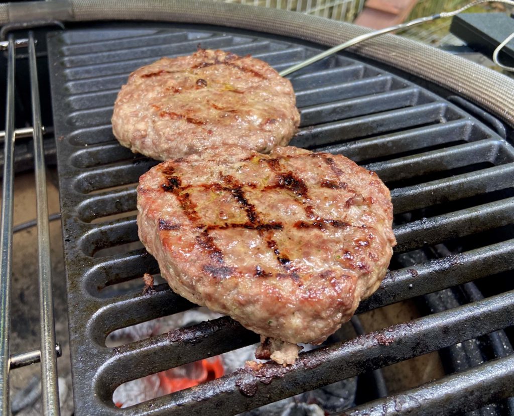 Les hamburgers de boeuf sont cuits au barbecue et on vérifie la température de cuisson avec une sonde.