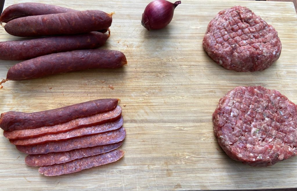 Les ingrédients principaux de notre recette: saucisses piquantes sèches, hamburger et oignon rouge.